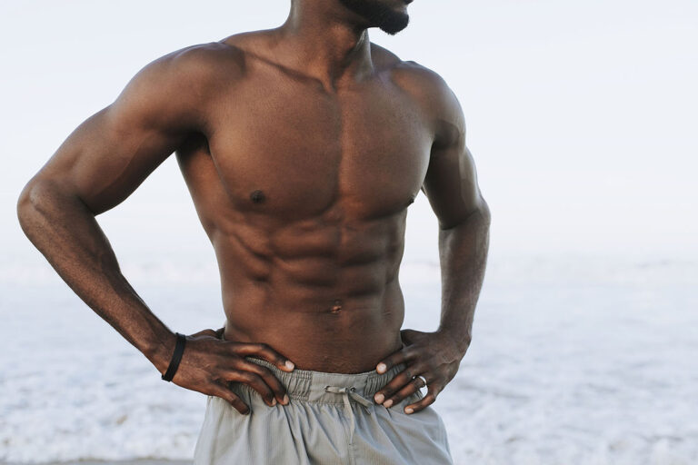 A muscular black man standing on the beach